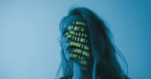 A woman on a blue background with a light projected on her face with the binary code representing the technology, as AI marketing, being applied for humans.